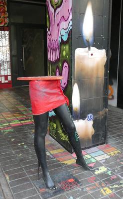 Table on top of the bottom half of a mannequin with red skirt and black legs.