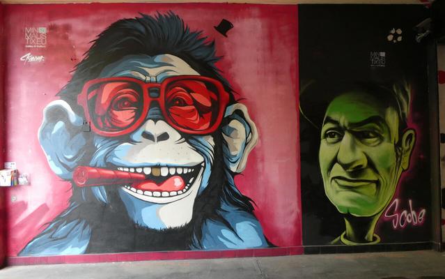 At left, an ape in red glasses, smoking a red cigarette. At right, a man with a green face
