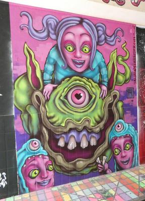 Smiling girl with pink skin and blue shirt riding a one-eyed green monster.