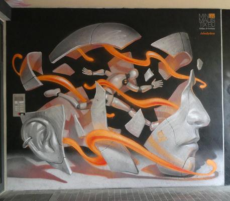 Robot running through a large human head that has been “exploded” into segments. Orange ribbons run throughout the picture.
