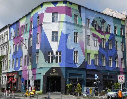 Building painted in abstract shapes of dark blue, light blue purple, light green, and white