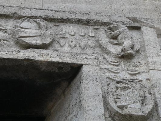 Circular carvings including a bear and a person’s face. Between them, carved branches with leaves