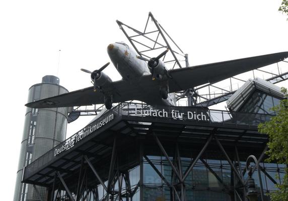 Exterior of Deutsches Technikmuseum, with propeller airplane mounted on roof.