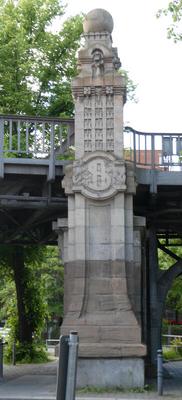 Stone column with sphere on top and what looks like a $ on the side