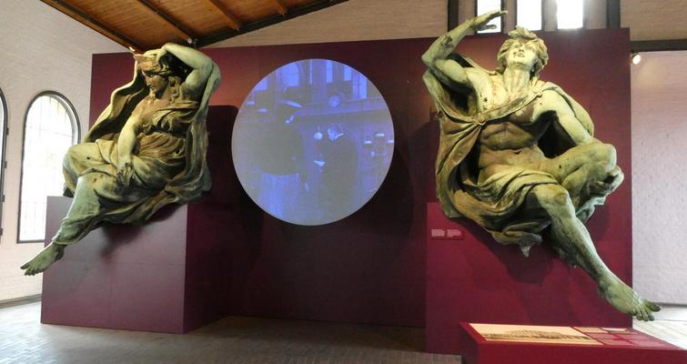Two classical statues flanking a video display showing old-time photos of railway personnel