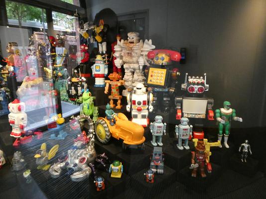 Display case of toy robots of various sizes and colors.