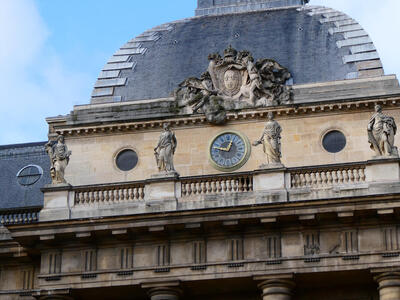 Clock at top of building with statues on either side.