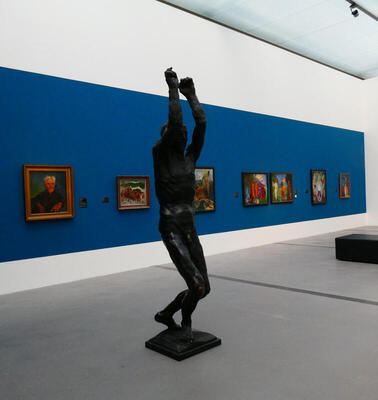 sculpture of man with paintings in background