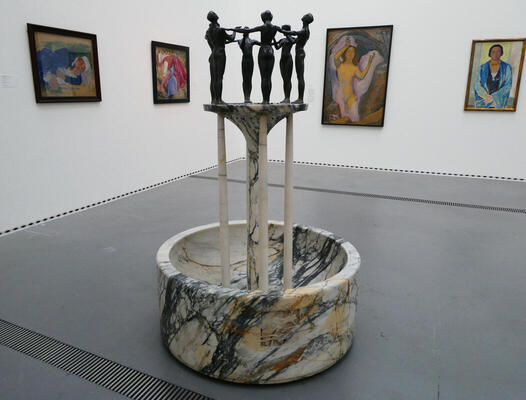 sculpture with ring of women and paintings in background