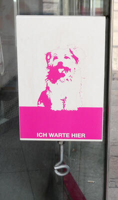 Place to leash dog; has cute picture of dog with words “Ich warte hier”