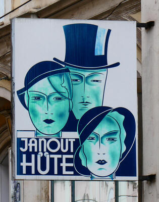 Hat store sign showing elegant ladies in 1920 style hats and man in top hat.