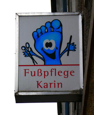 Fußpflege Karin (cartoon foot with happy face holding scissors and nail file)