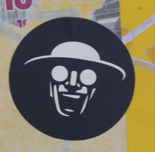 Grinning man with round eyeglasses and hat like a pith helmet.