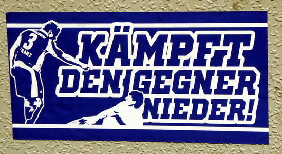 Soccer player pointing at opposing player on ground: Kämpft den Gegner nieder!