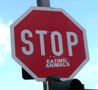 Stop sign with sticker reading “eating animals“ added to it.