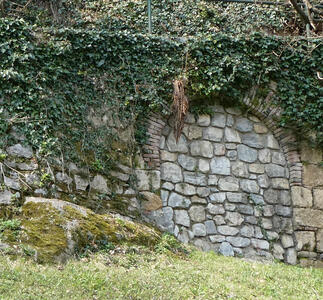 Filled-in stone arch surrounded by green leaves