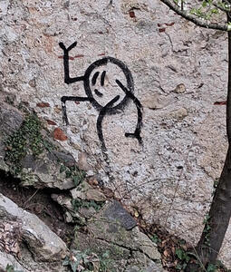 Stick figure of a man climbing up a steep wall.