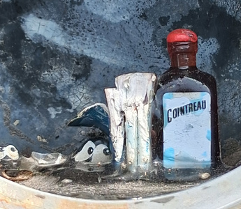 Closeup of the tiny bottle of Cointreau, what look like small pieces of paper, and a couple of pair of googly eyes.