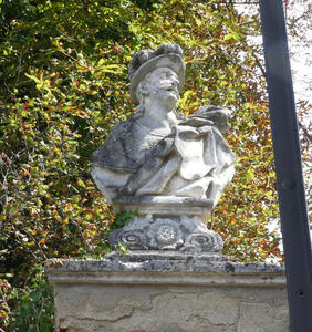 Stone bust of man with beard and moustache. He is wearing a plumed helmet.