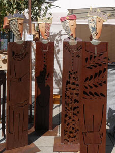 Four ceramic heads with pattern on half the face like a harlequin. The busts are on metal columns.