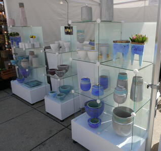 Blue ceramic bowls and jars on clear glass shelves.