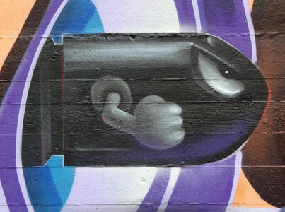 Side view of anthropomorphic bullet flying through air; fist clenched and angry stare in eye.