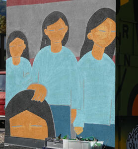 Four women; three wearing light blue shirt and blue pants. Fourth woman you can only see their head