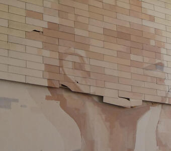 Closeup of bricks above and smooth wall below.