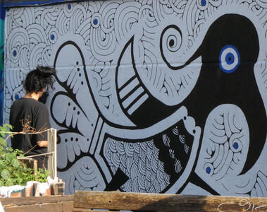 Artist working on a painting of a bird with geometric swirls in background