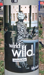 Person in zebra costume at an office desk. Text: wirkt wild. vielvielkoffein