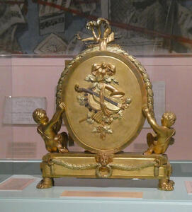 Gold oranment with picture of stringed instrument on it.