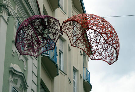 Wire-frame umbrellas hanging from a line stretched across a street