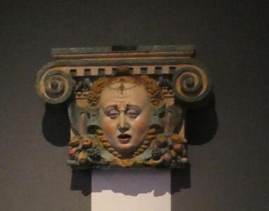 Top of a column showing the head of a red-haired woman. She has a weary expression on her face.