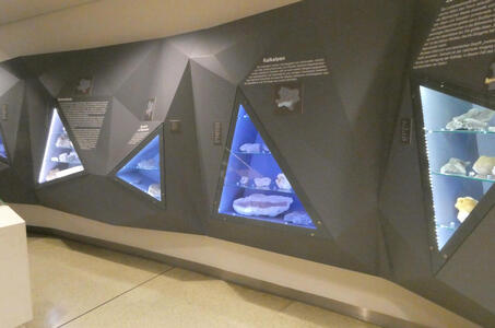 Room with display cases of minerals and crystals. The displays have triangular windows.