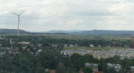 View of farmland. At left, a tall wind turbine.