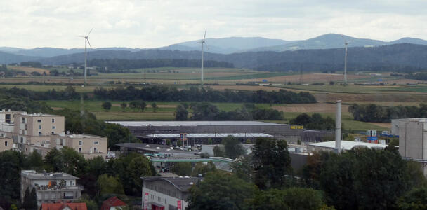 Industrial buildings in foreground; farmland with several wind turbines in background.