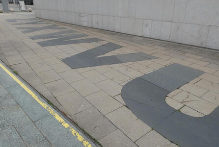 Letters ZYXWVU in black asphalt tiles on sidewalk.