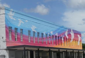 Wall painting of birds in blue sky and sunset colors at bottom