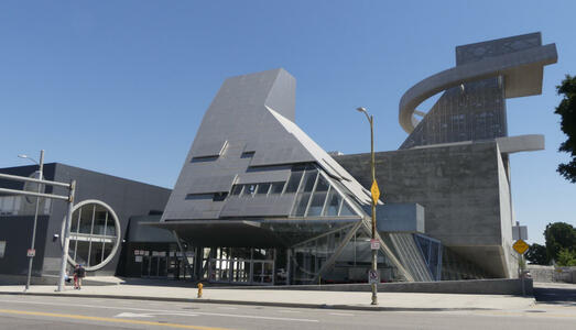 Side of school, canted metal structure and round window-like portal at left