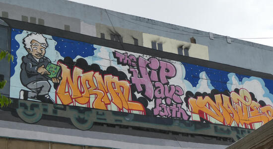 Graffiti mural of man holding book, words NORMAL and HP HAVE FAITH