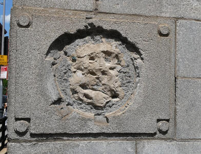 Plaque on cornerstone with badly weathered relief face