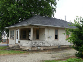 Dilapidated house with no glass in windows; door open