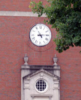 Clock with roman numerals on brick building above portico
