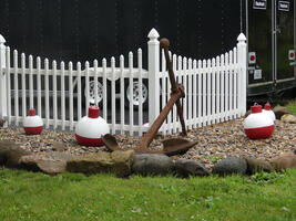 Anchor and red and white buoys in front of a white picket fence