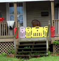 Front porch of house with “fence” of colorful plastic float boards.