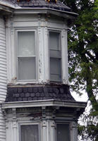 Closeup of peeled paint on windows and missing/loose shingles