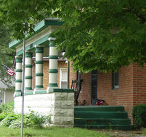 Porch with four white columns; each column has four green bands on it