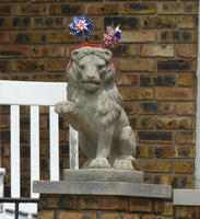 Stone lion with headband with two red white and blue whirligigs on it.