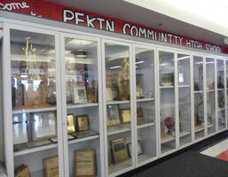 Trophy case displaying trophies, plaques, and team photos