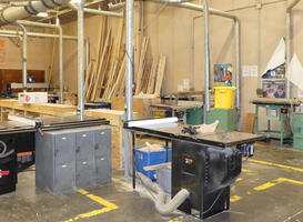 Construction classroom with wood stacked on walls and power saws in foreground